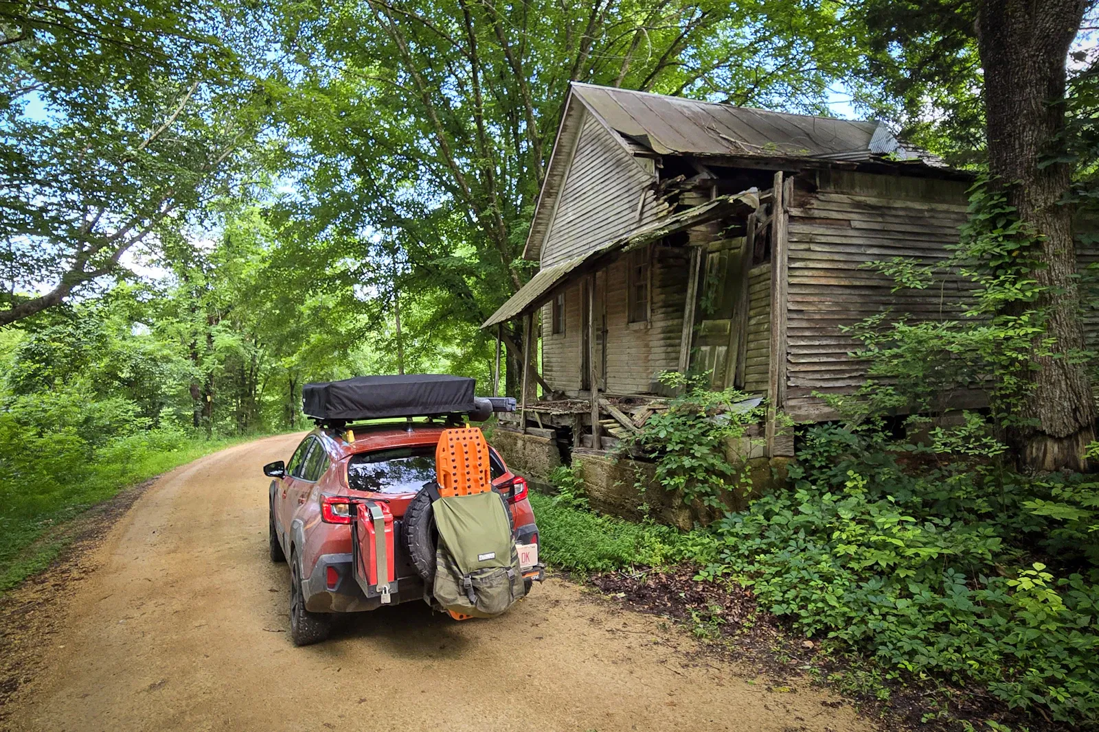 The gear layout — RiG'd Supply UltraSwing on the rear, MAXTRAX traction boards, recovery kit, and the rooftop tent closed for travel.