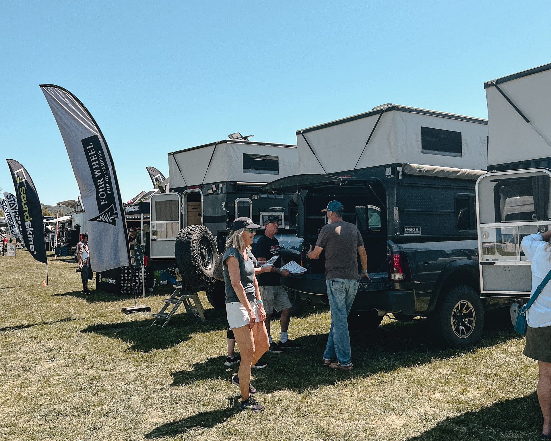 Show floor at the Backcountry Offroad Expo with overland rigs and crowds at golden hour