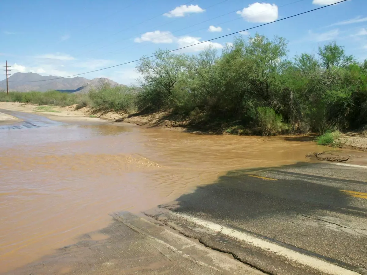 A flash flood near Tucson, Arizona, with muddy water and debris covering the road.