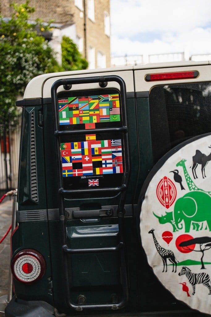 Stock INEOS Grenadier Trialmaster with country flags, parked at The Grenadier pub in London.