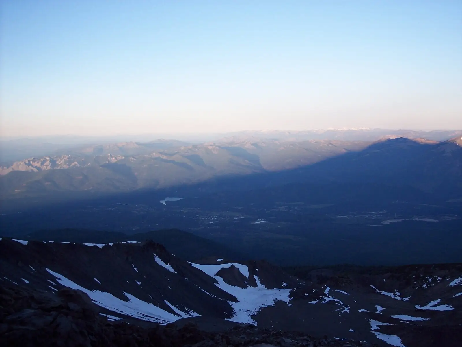 Mount Shasta's shadow cast at 5:57 AM from high on the west face — a 14,179-foot peak in morning light.