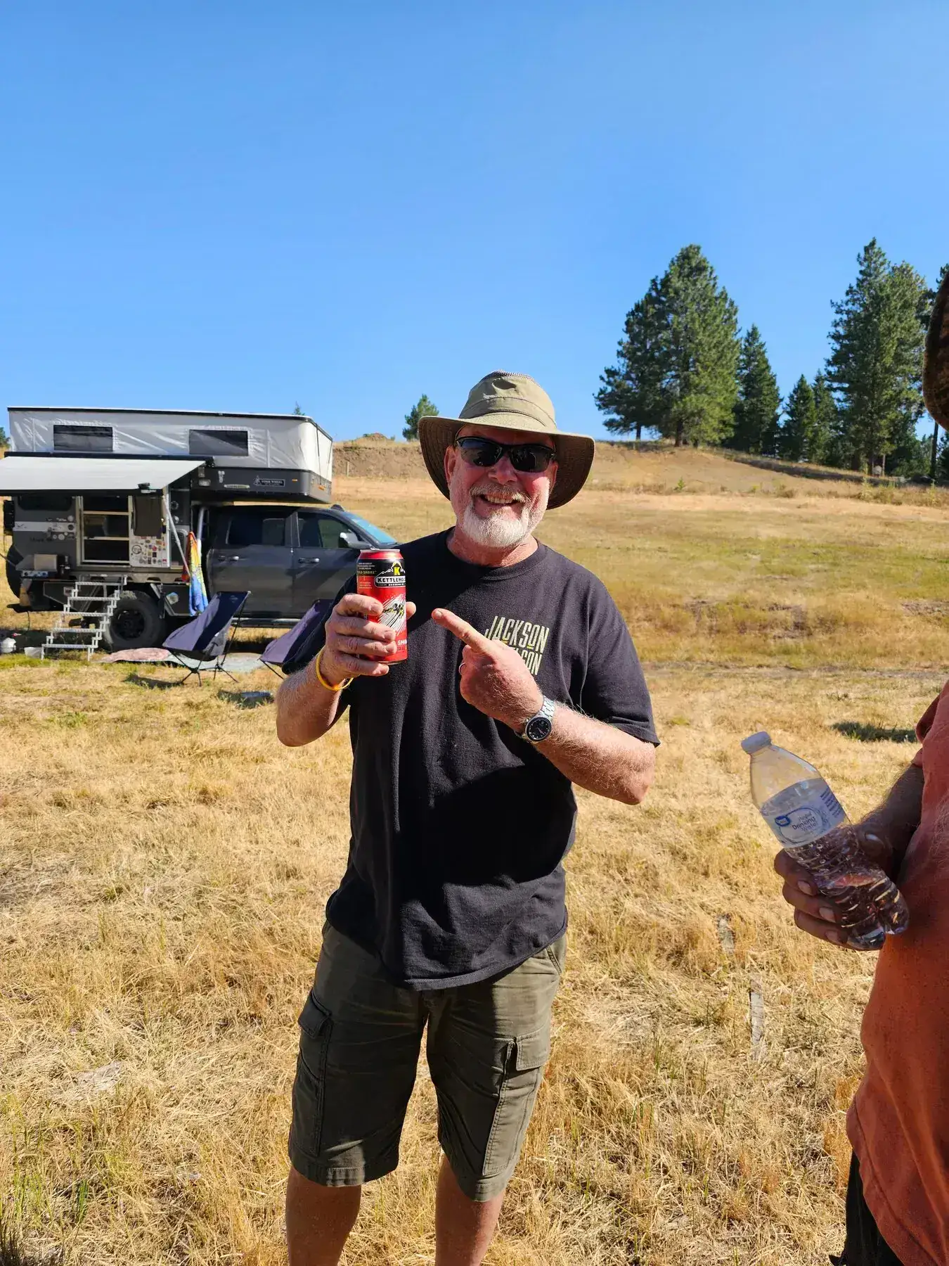 Man pointing to a beverage can at a campsite