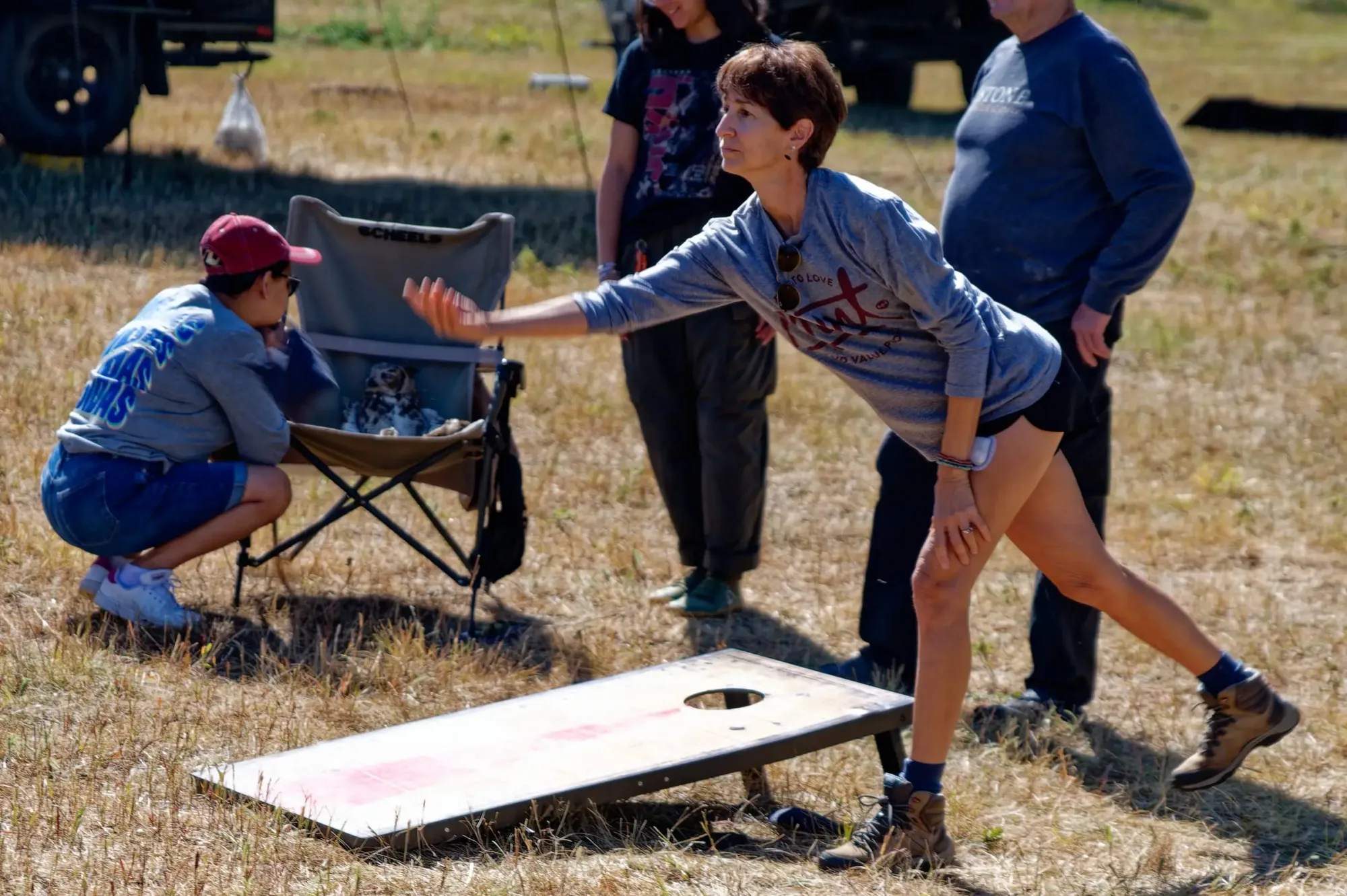 People gathering around a cornhole board outdoors