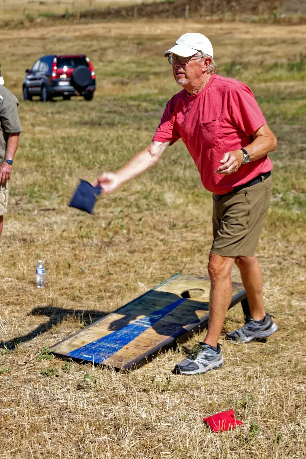 Man tossing a beanbag toward a cornhole board