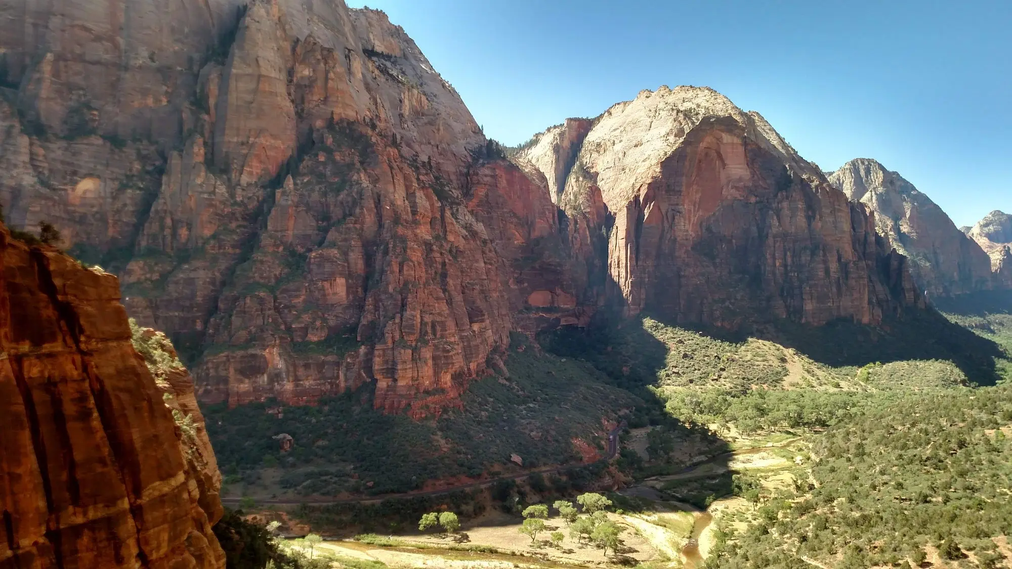 Red sandstone canyon with a green valley, river, and road
