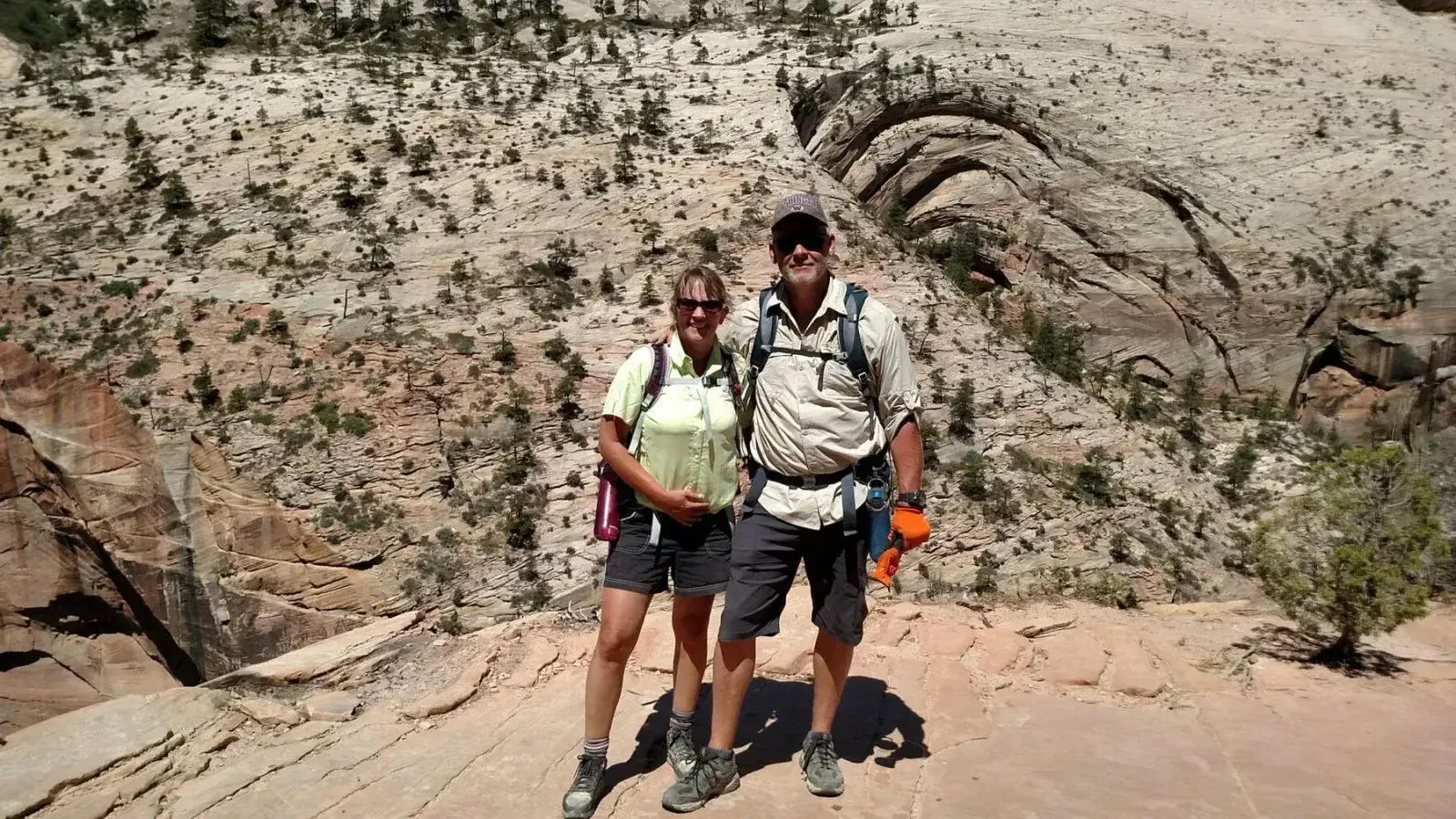 Two hikers on a sandstone overlook above a canyon