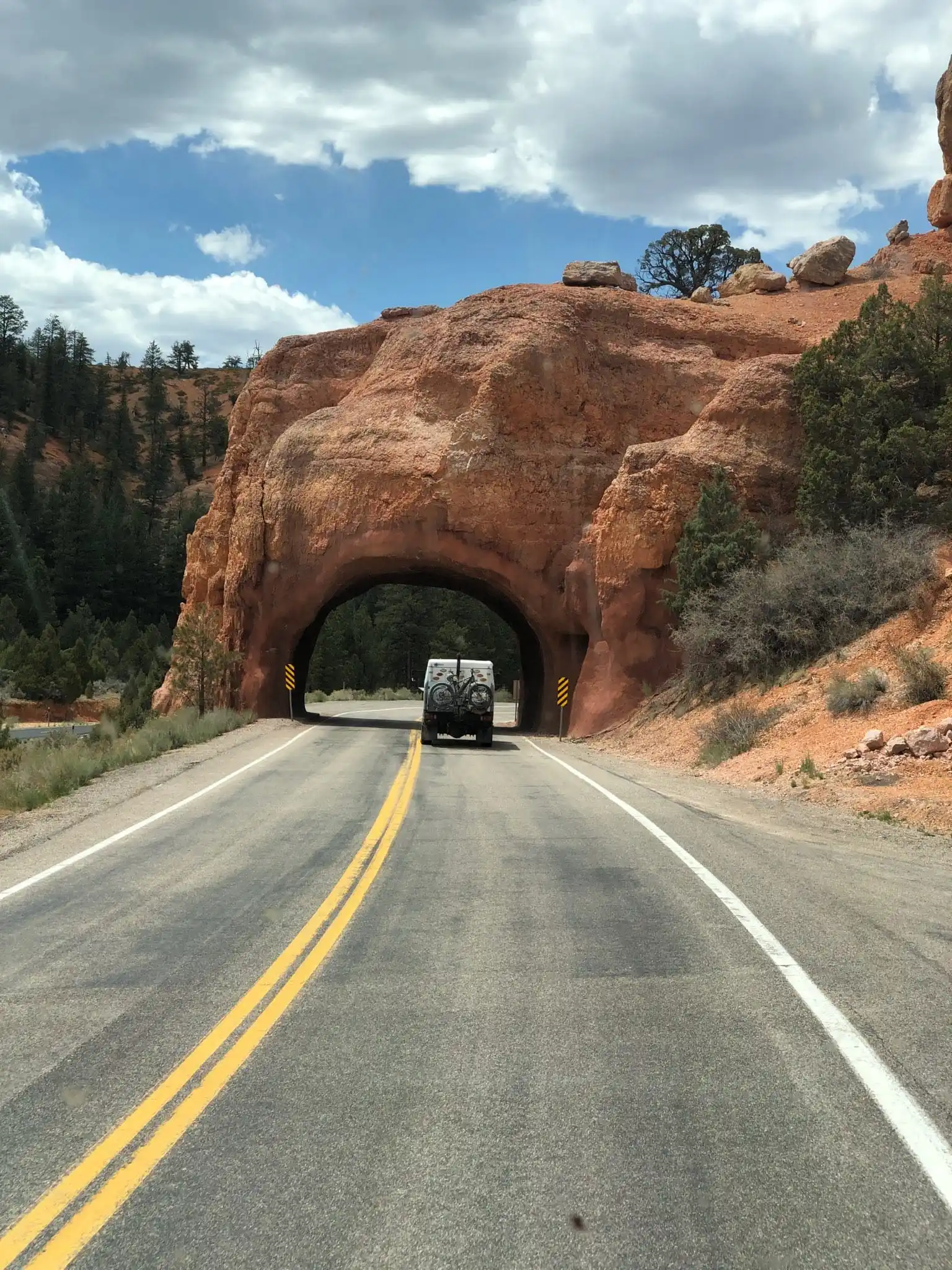 Two-lane road entering a tunnel through red sandstone
