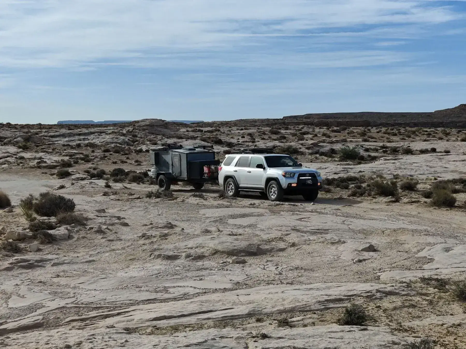 SUV towing an off-road trailer across a desert landscape