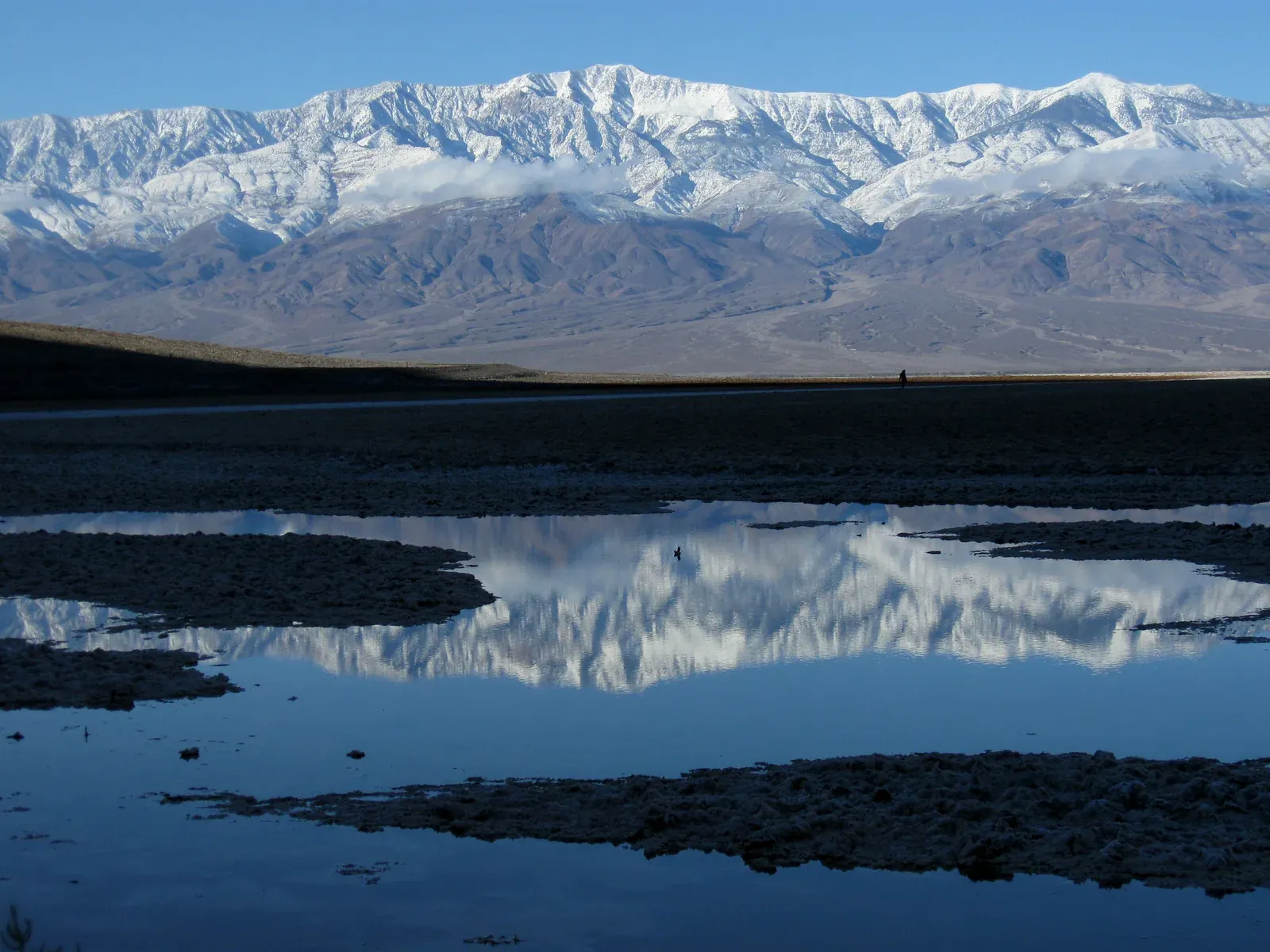 Snowy Telescope Peak reflected in a shallow pool at Badwater Basin after rain