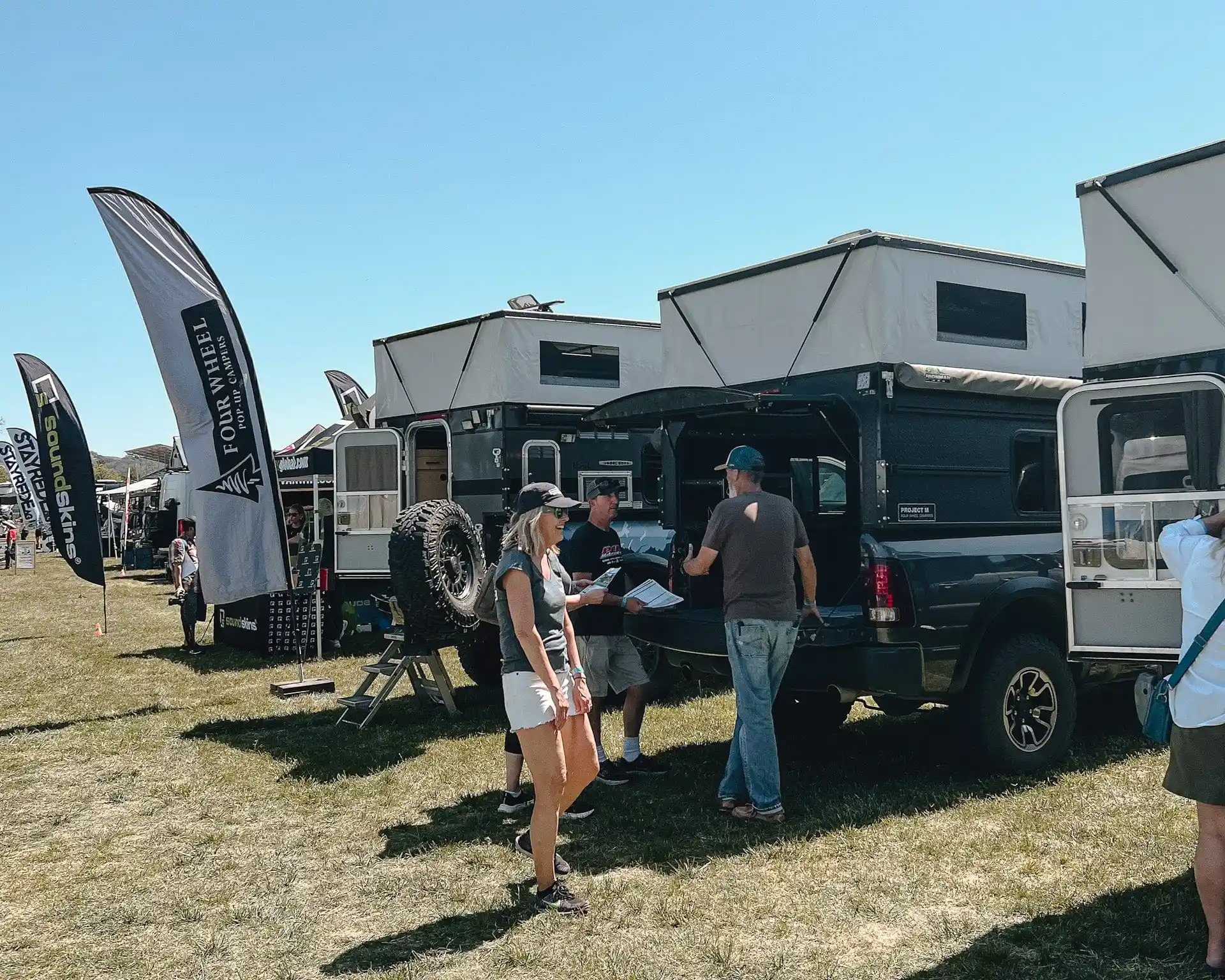 Show floor at the Backcountry Offroad Expo with overland rigs and crowds at golden hour
