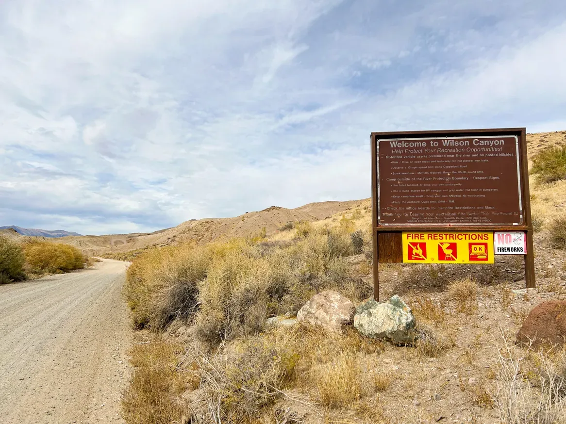 An informational BLM sign on Copperbelt Drive listing regulations, contact information, and fire restrictions