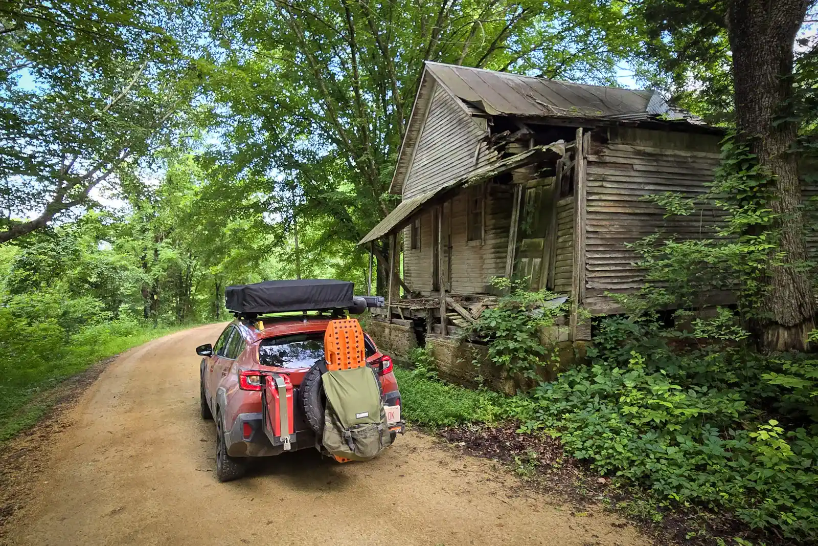The gear layout — RiG'd Supply UltraSwing on the rear, MAXTRAX traction boards, recovery kit, and the rooftop tent closed for travel.