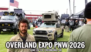 Steven Marty at Overland Expo PNW 2026 in front of a black Ford truck and tan Toyota Tacoma with rooftop tent